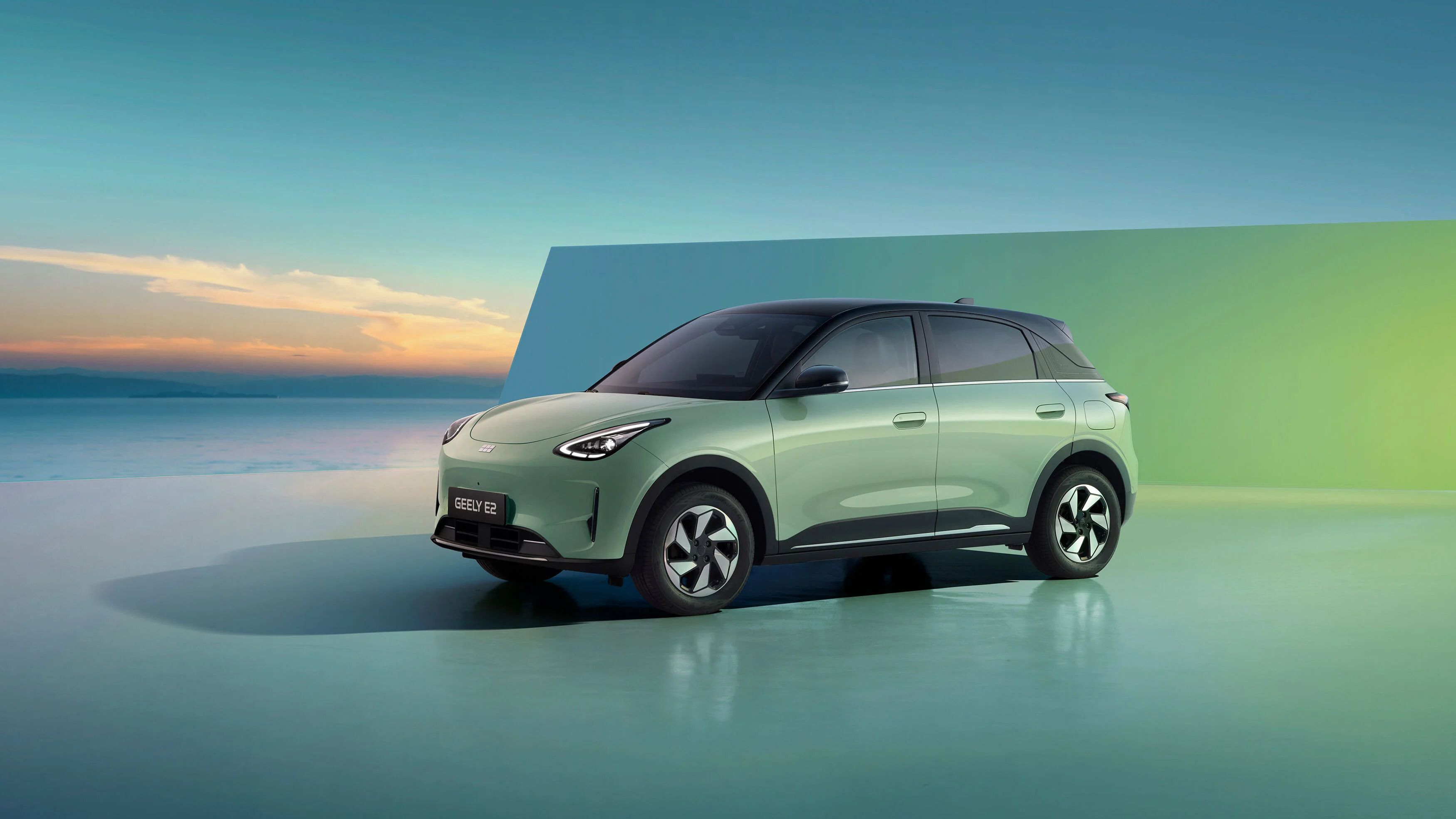 Geely E2 verde con techo negro visto de perfil en un entorno moderno